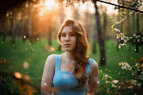 Hermosa joven en un vestido azul en un parque de primavera —  Fotos de Stock