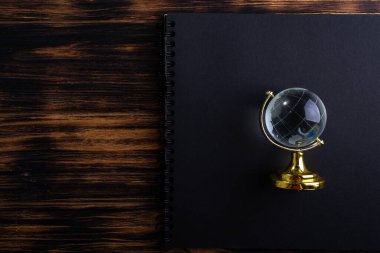 Ahşap bir arka planda siyah bir not defterindeki cam küre.