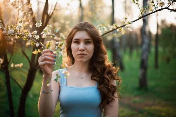 Hermosa joven en un vestido azul en un parque de primavera —  Fotos de Stock