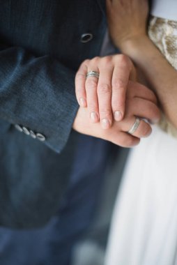 Damat ve gelin elleri bulanık arkaplanda yüzükler.