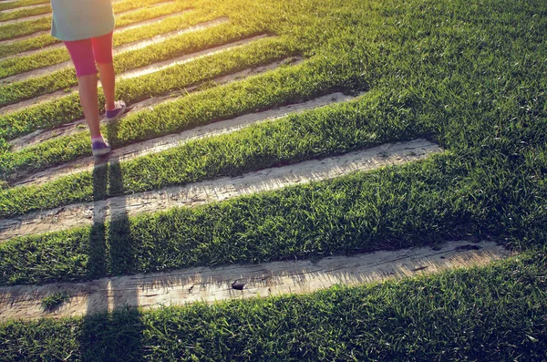 Girl walking on trail over green grass — Stock Photo, Image
