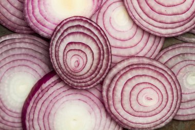 Üstten bakıldığında paslı metal bir masada mor soğan dilimleri.