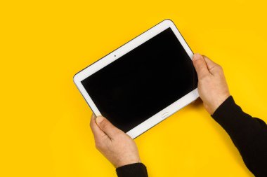 Sarı arka planda elinde tablet tutan bir adam.