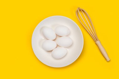 Tabakta beyaz yumurtalar ve sarı bir arka plan.