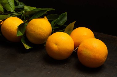 Paslı metal bir masada koyu bir arka planda portakallar.