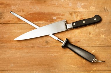 Çelik bileyicisi ve mutfak bıçağı kırsal bir ahşap masada, üst tarafta.