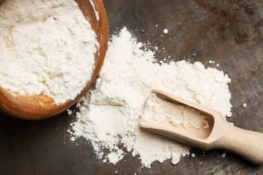 Tahta bir kasede un ve paslı metal bir masada tahta bir kaşıkta