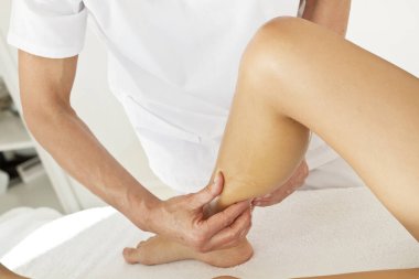 Bacaklarındaki bir kadına masaj ve fizyoterapi
