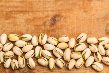 Ahşap bir masada soyulmamış yeşil şam fıstığı.