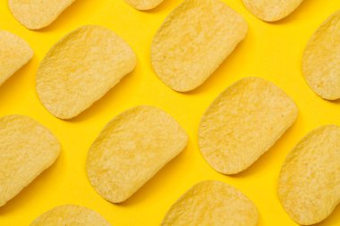 Sarı arka planda bir sürü patates cipsi var.