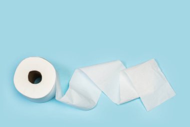 Açık mavi arkaplanda üst görüntüde bir tuvalet kağıdı rulosu