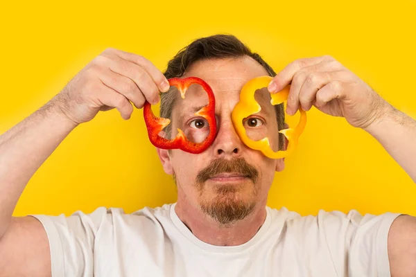 Mężczyzna Trzyma Plasterki Czerwonej Żółtej Papryki Oczach Jak Okulary Żółtym — Zdjęcie stockowe