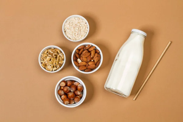 Een Fles Melk Met Noten Witte Schalen Een Bruine Achtergrond — Stockfoto