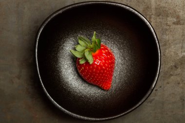 Siyah kasede bir çilek, en tepede.