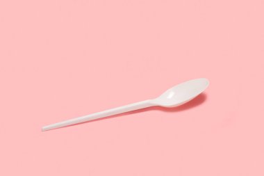 Pembe arka planda tek kullanımlık plastik kaşık.