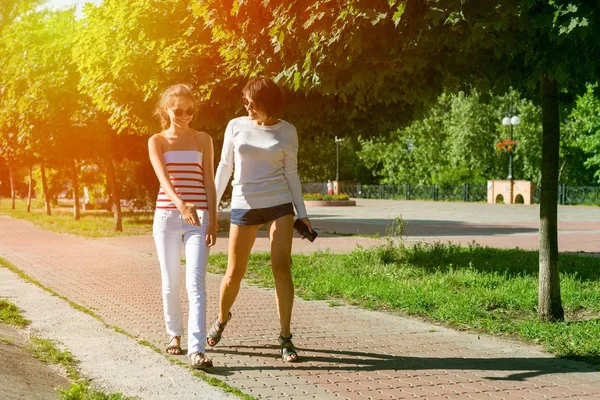 Mom and daughter talking, smiling, walking through the city park — Stock Photo, Image