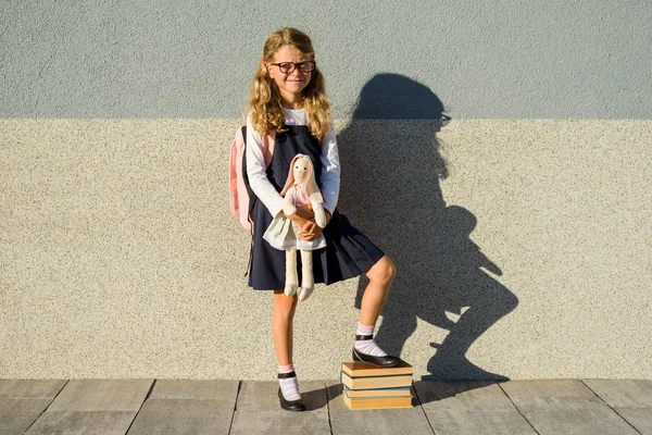 Una linda colegiala de la escuela primaria está sonriendo con un juguete en su —  Fotos de Stock