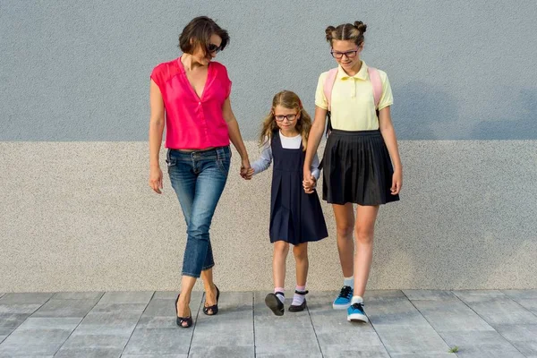 Anne ve kızı öğrenciler el ele tutuşarak okula gitmek. 