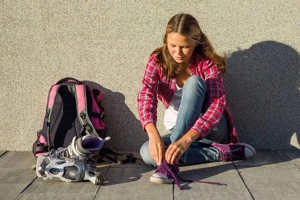 Chica adolescente quita zapatillas de deporte y ropa patines al aire libre . — Foto de Stock