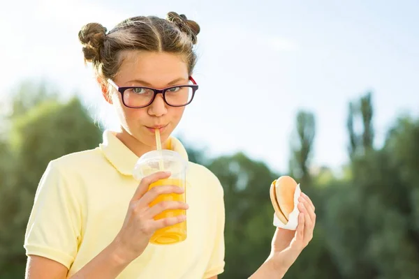 Söta leende tonåringen i skoluniform som innehar en hamburgare och — Stockfoto