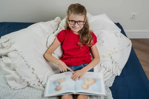 Ένα όμορφο κορίτσι με τα γυαλιά, ένας μαθητής του δημοτικού σχολείου ανάγνωση — Φωτογραφία Αρχείου