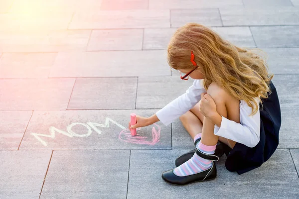 Una colegiala linda dibuja una tiza colorida en la acera de LOVE MOM . —  Fotos de Stock