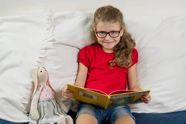 Una chica guapa con gafas, una estudiante de primaria leyendo — Foto de Stock