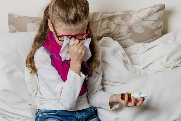 Linda niña en gafas estornudando en un tejido soplando —  Fotos de Stock