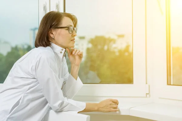 Retrato de vista lateral de uma médica olhando pela janela — Fotografia de Stock