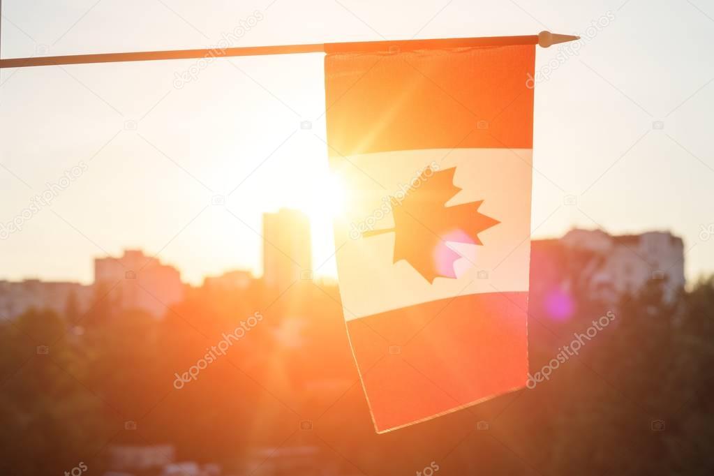 Flag of Canada from window on sunset background
