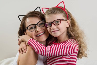 Kızı annesi sevgiyle kucaklıyor. Üst ve alt sol