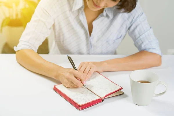 Woman with a notebook sitting at a table — Stock Photo, Image