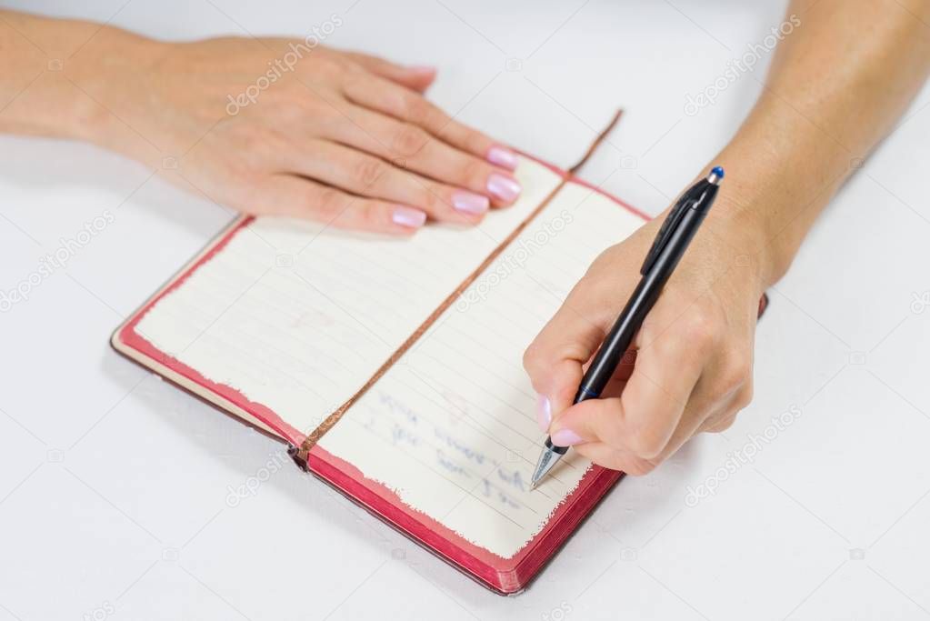 Hand writing in open notebook on table