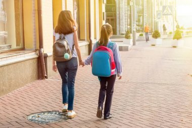 Arkadan Görünüm, kız öğrenciler el ele tutuşarak okula gidiyorum..