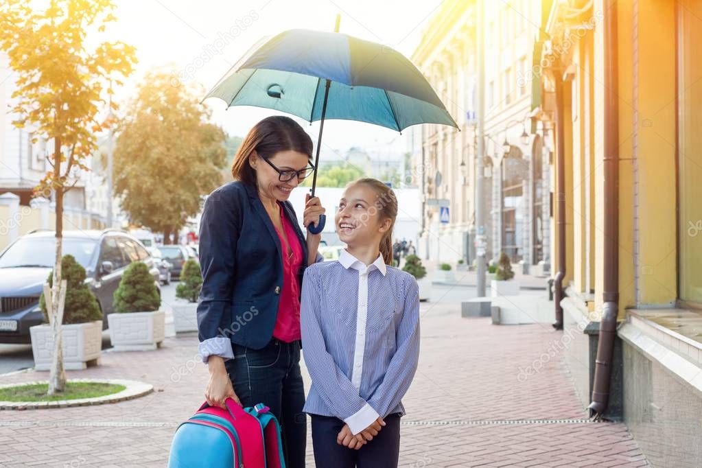 Beautiful woman with daughter walking together to school under a