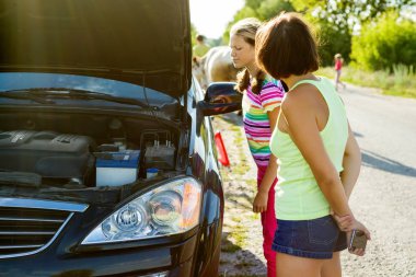 Kırık bir araba yakınındaki bir ülke yolda bir çocukla bir kadın sürücü