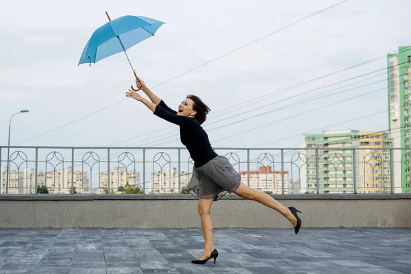 Žena vede za deštník na pozadí města — Stock fotografie