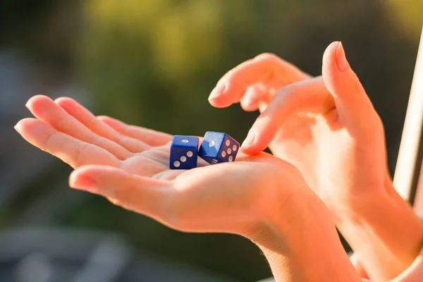 Dobbelstenen in de vrouwelijke hand, zonsondergang achtergrond. Gokken apparaten. — Stockfoto