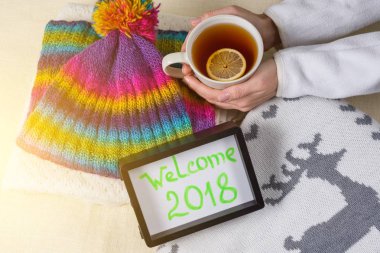 Hoşgeldiniz 2018, çerçevedeki metin. Kış giyim arka plan ve limonlu sıcak çay.