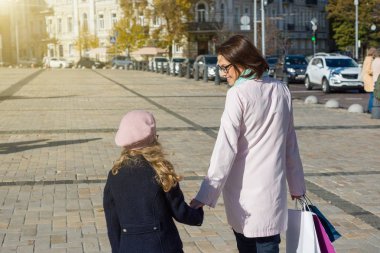 Kadın ve küçük kızı ile alışveriş torbaları street yürüyüş