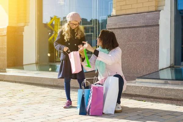 Small fashionable girl and mom happy - looking at purchases in shopping bags. — Stock Photo, Image