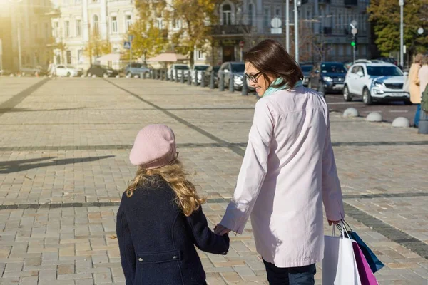 ผู้หญิงกับลูกสาวของเธอ พร้อมถุงช็อปปิ้ง เดินไปตามถนน — ภาพถ่ายสต็อก