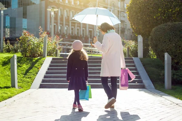 Mujer y su hija pequeña con bolsas de compras caminando por la calle —  Fotos de Stock