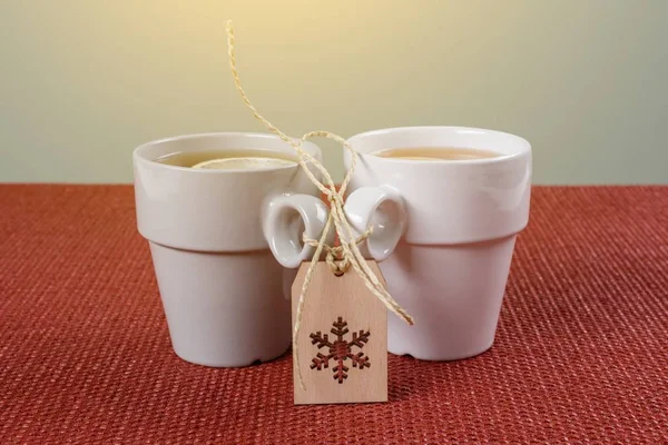 Un par de tazas de té con un limón en la mesa, un copo de nieve de invierno. Vacaciones, Navidad, invierno, comida y bebidas concepto . — Foto de Stock