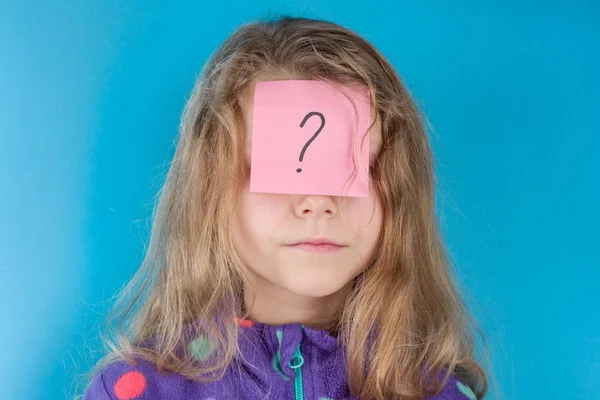 Menina e adesivo ponto de interrogação na testa, fundo azul — Fotografia de Stock