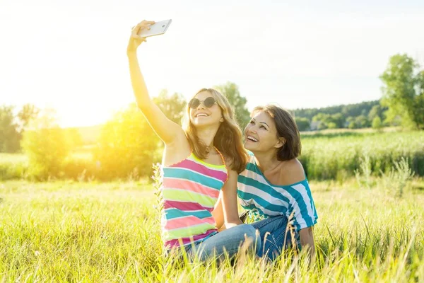 Gyönyörű felnőtt anya és lánya tizenéves lány így egy selfie, használata egy okos telefon, és mosolyogva portréja. — Stock Fotó