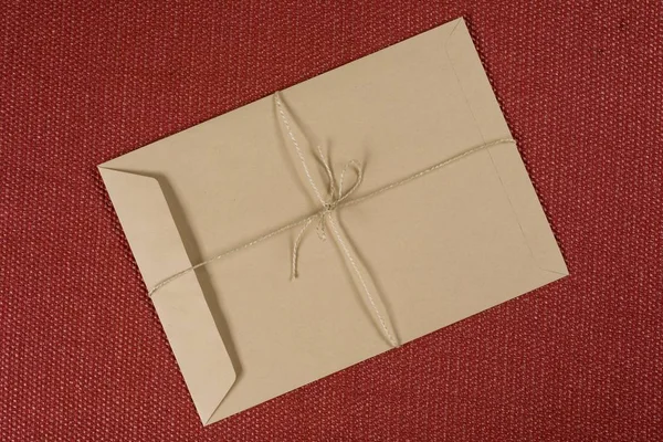 Sobres de papel artesanal marrón vacío sobre un fondo texturizado con cuerda artesanal — Foto de Stock