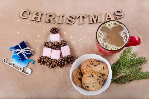 Karácsonyi ünnep háttér a szán, csésze kávé, süti, kúp és fehérmályva formájában egy karácsonyfa a díszdobozban. Kraft papír háttér, látkép fentről. — Stock Fotó