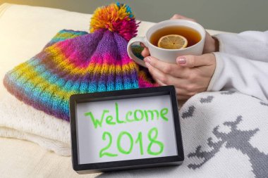 Hoşgeldiniz 2018, çerçevedeki metin. Kış giyim arka plan ve limonlu sıcak çay.