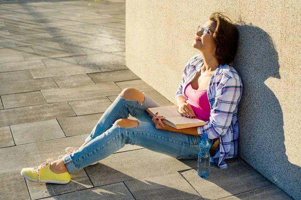 Sonriente hermosa morena relajante al aire libre y libro de lectura — Foto de Stock